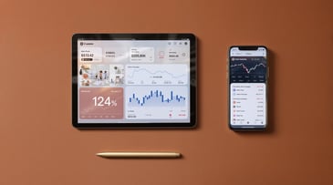 Tablet and smartphone displaying financial analytics and data visualization on a brown background with a pen.